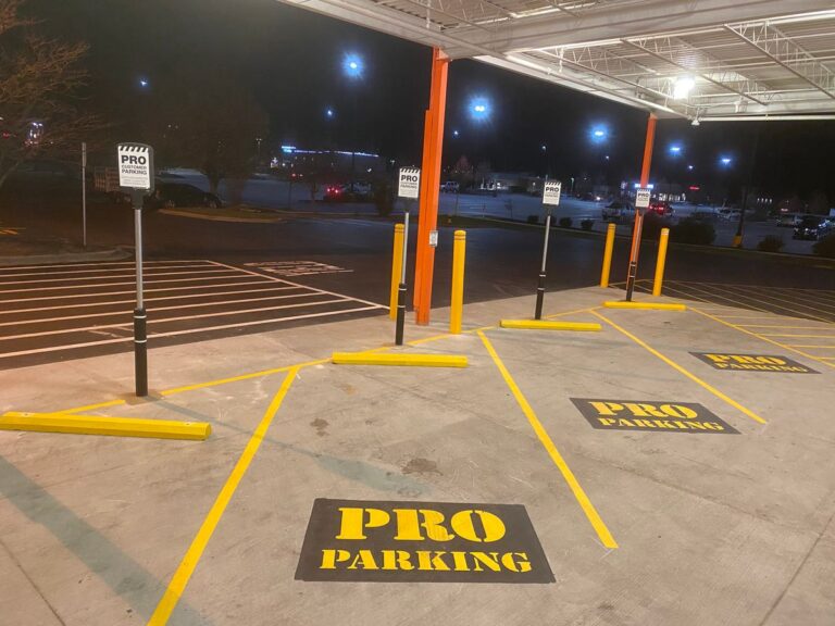 Retail store pro parking area with yellow wheel stops, bollards, signs, and pavement markings.