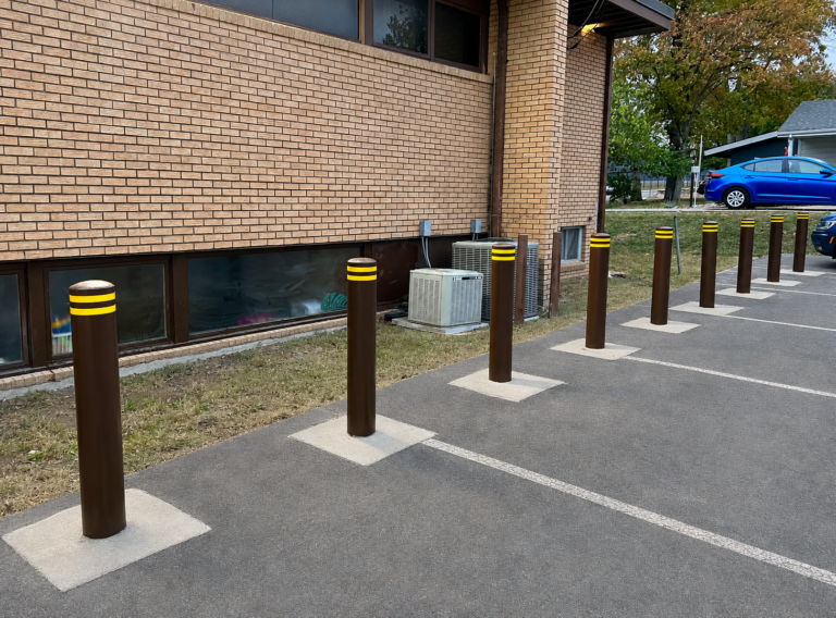 Brown bollards installed along a church parking lot beside a building.