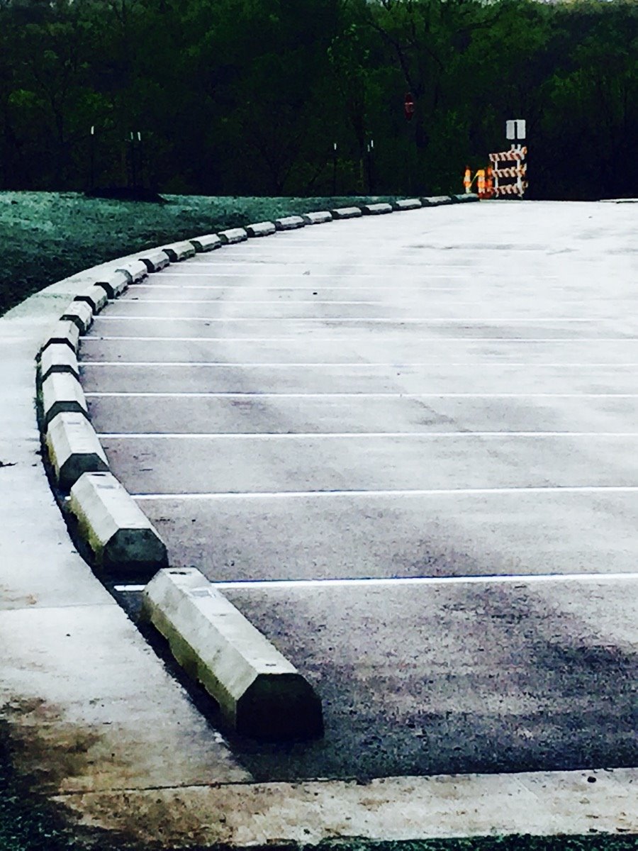 Concrete wheel stops installed along a curved commercial parking lot curb.