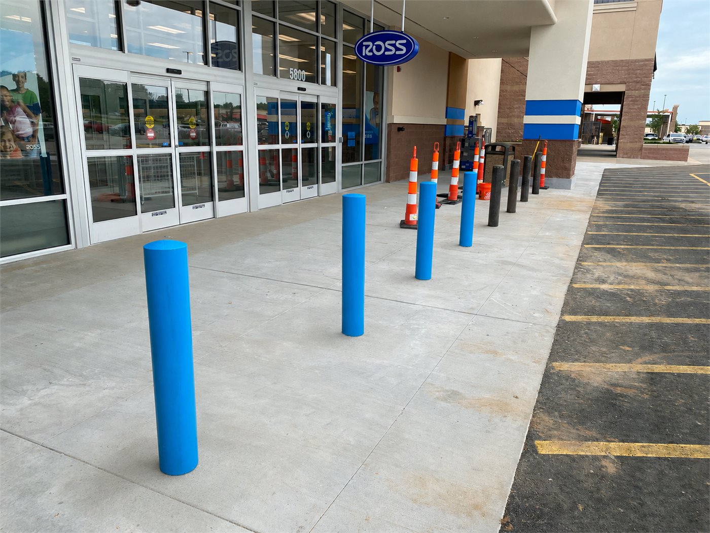 Blue bollards installed outside a retail store entrance in Merriam, Kansas.